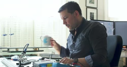 Man Soldering Electrical Components at Desk