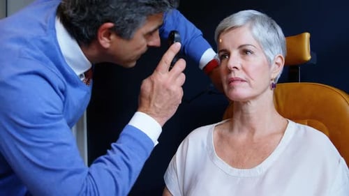 Doctor Examines Mature Woman's Eyes with Ophthalmoscope