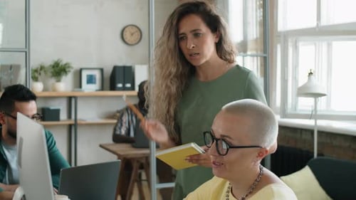 Two Businesswomen Discussing Project on Computer in Office
