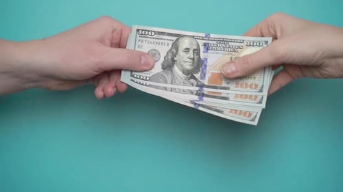 Hands Exchanging Hundred Dollar Bills on Blue Background