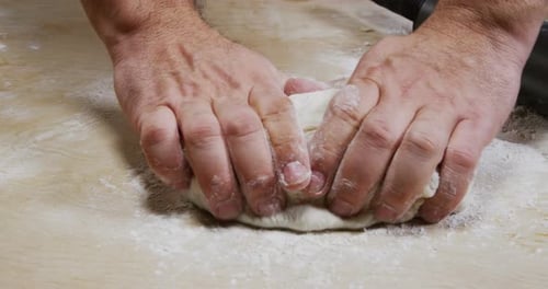 Hands Kneading Dough for Baking on Wood Surface
