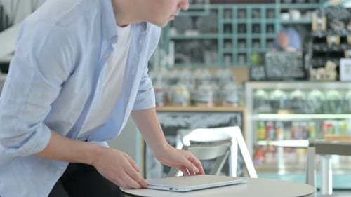 Man Opens Laptop to Work at Cafe Table