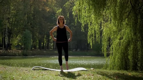 The Girl Performs Warmup Exercises Before Yoga in Nature n Park