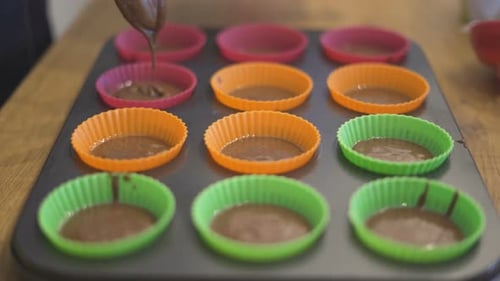Chef's Hands with Spoon Fill Chocolate for Baking Muffins in Paper Cups