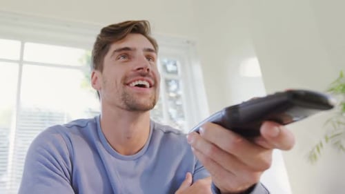 Man Laughing While Holding a Television Remote