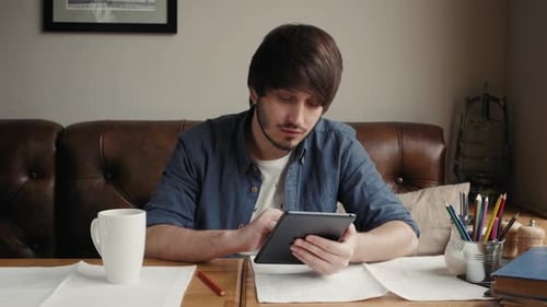 Busy Man Freelancer Work on Tablet in a Cafe, Drinks Coffee and Eats, Business Man with a Beard Sits