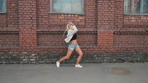 Woman Dancing in front of Brick Wall