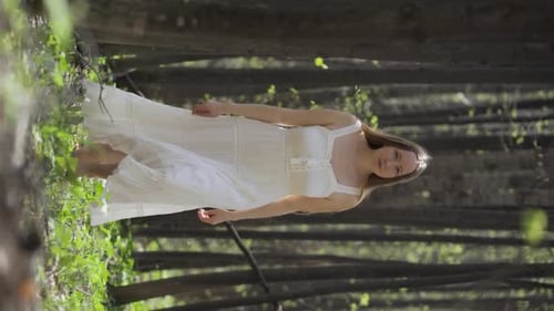 A Beautiful Fabulous Woman in a Light White Dress Walks Barefoot Through the Forest