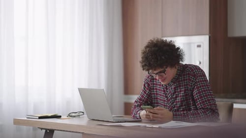 Young Adult Using Smartphone at Desk at Home
