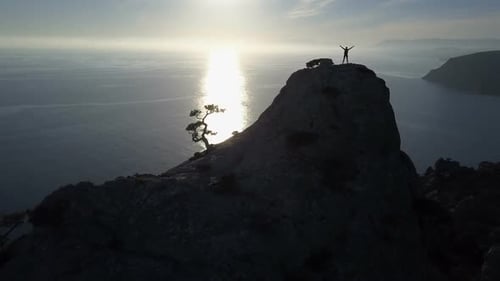 Flight Over a Young Woman Standing on the Top of a Mountain Facing the Sea. Lady on the Summit