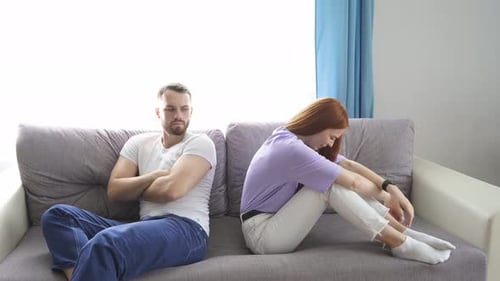 Upset Couple Sitting on Sofa After Argument