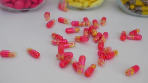 Colorful Pills Falling Onto White Surface