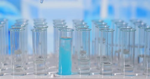 Blue Liquid Being Added to Test Tube Rack