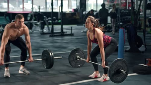 Hombres y mujeres atletas hacen peso muerto con barra, los culturistas entrenan, hacen gimnasio