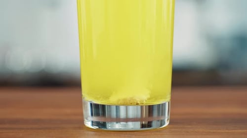 Yellow Effervescent Tablet Dissolving in Glass of Water