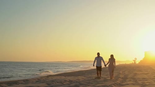 Young Beautiful Couple Running on a Sandy Beach By Sea