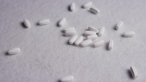 Scattered White Pills on Textured White Surface