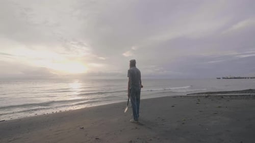 Middle Aged Man Treasure Hunter in Headphones with a Metal Detector Works on the Ocean Sand Beach at
