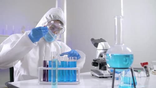 Wissenschaftler in der PPE-Suite, die einige Nachforschungen anstellt, um eine Flüssigkeit in einem Reagenzglas im Labor zu überprüfen.