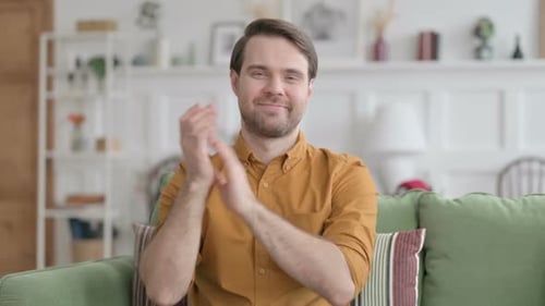 Man Smiling and Clapping on Green Couch