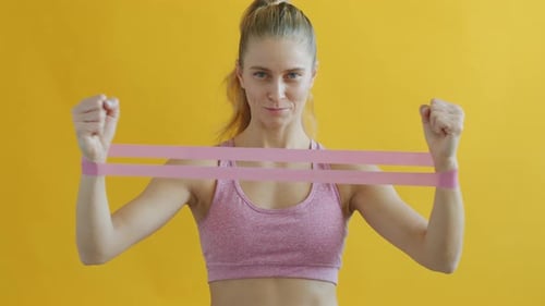 Blonde Woman Exercises with Resistance Band Indoors