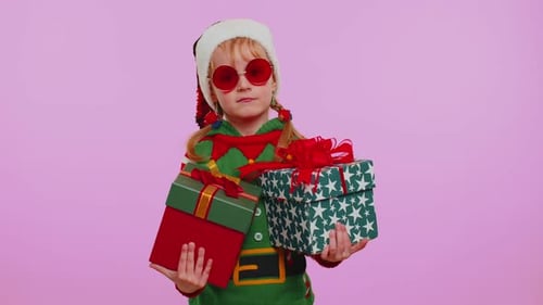 Smiling Child in Elf Costume Holding Christmas Gifts