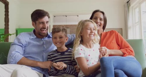Family Laughing Together on Sofa at Home