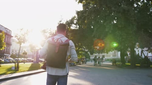 Attractive Young Handsome Man Tourist with Backpack Walking in City Center and Looking Around Slow