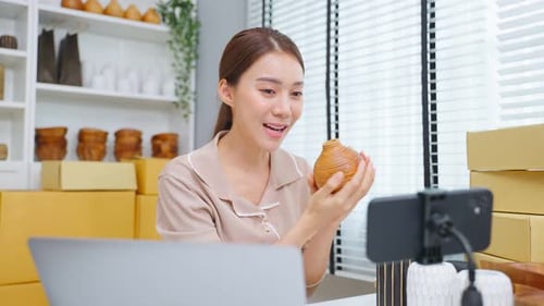 Asian beautiful woman sell vase product online live streaming at home.