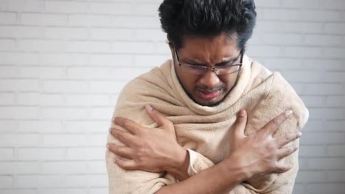Homme malade avec une couverture assis sur le lit
