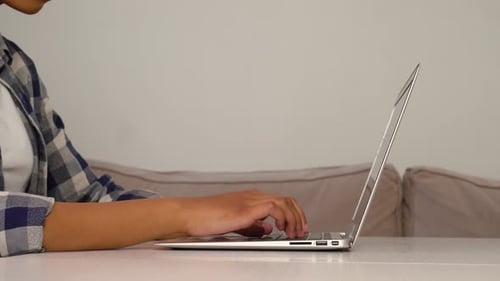 Young Adult Typing on Laptop at Table