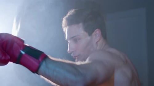 Intense Boxer Training with Punching Bag in Gym