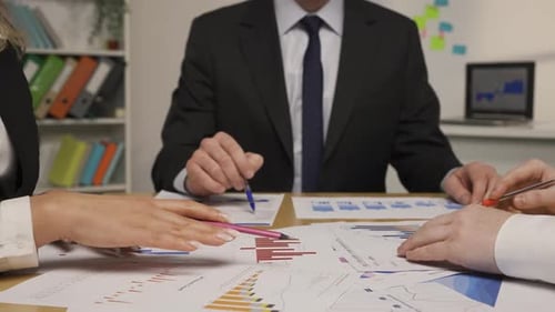 Leader Man and Business Partners Analyze Papers with Charts and Graphs
