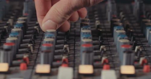 Sound engineer working in a recording studio with a sound console and microphones