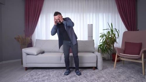 Man Grips Head, Falls in Living Room