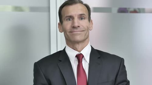 Businessman Smiling and Winking in Office Setting