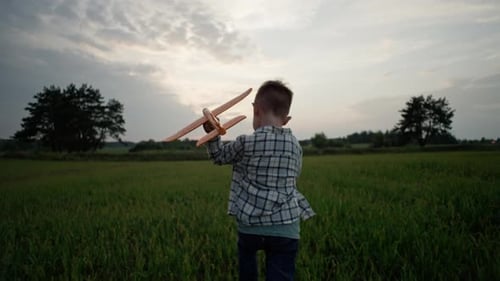 Boy Runs With Toy Plane in Grassy Field