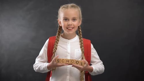 Joyful Female Child Holding Wooden Cubes With School Word, First-Former Kid