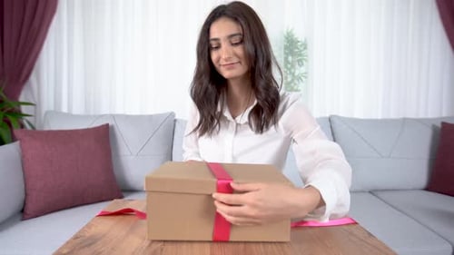 Woman Wraps Gift with Pink Ribbon at Home