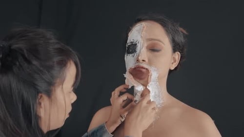 Make up artist make a zombie mask on woman's face and neck for costume party