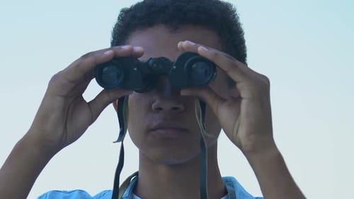 Afroamerikanischer Teenager schaut durch Fernglas