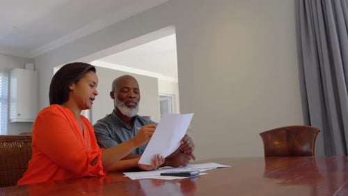 Front view of mature black couple discussing domestic bills in a comfortable home 4k
