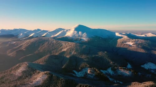 Aerial sunrise Landscape Sun Light Touches Mountain Tops. Flying above Winter Forest.