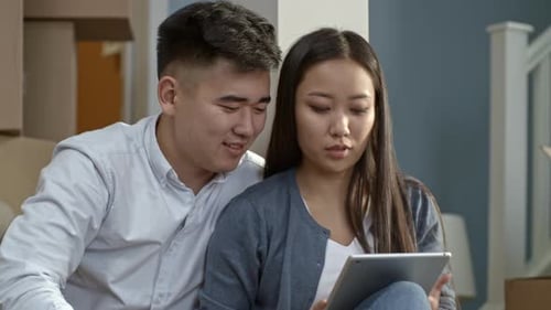 Couple using tablet in new home with boxes