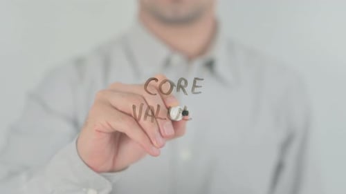 Adult Writing Core Values on Clear Surface