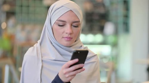 Portrait d'une jeune femme arabe concentrée utilisant un smartphone