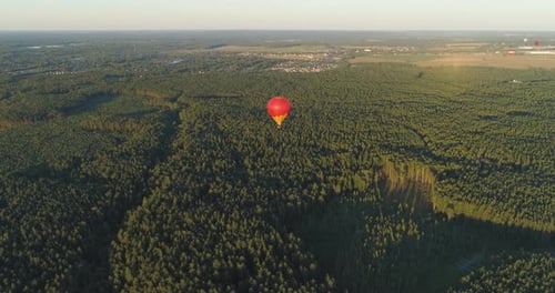 Hot Air Balloon Soaring Over Green Forest Landscape