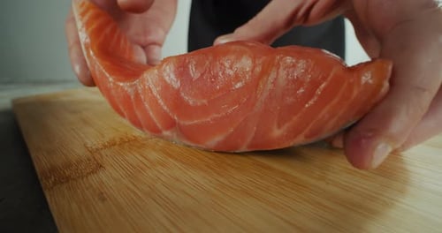 The Chef Puts a Piece of Fish on a Wooden Board for Slicing Close Up Footge