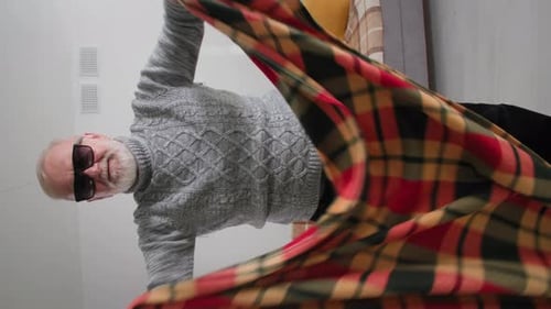 Senior Adult Holds Plaid Blanket Indoors