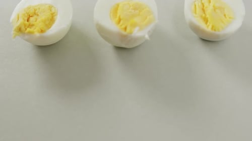 Vídeo de primer plano de tres mitades de huevos duros sobre fondo gris